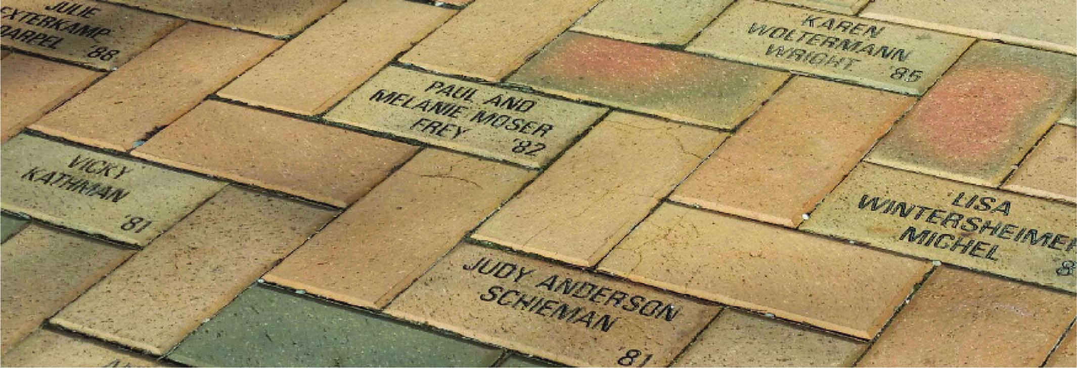 A close up of a brick walkway showing various commemorative bricks donated from different years.