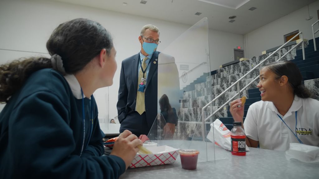 The Principal, Jack VonHandorf, stopping to say hi to students eating lunch in the cafeteria at the Notre Dame Academy catholic all-girls school in Covington, Northern Kentucky.