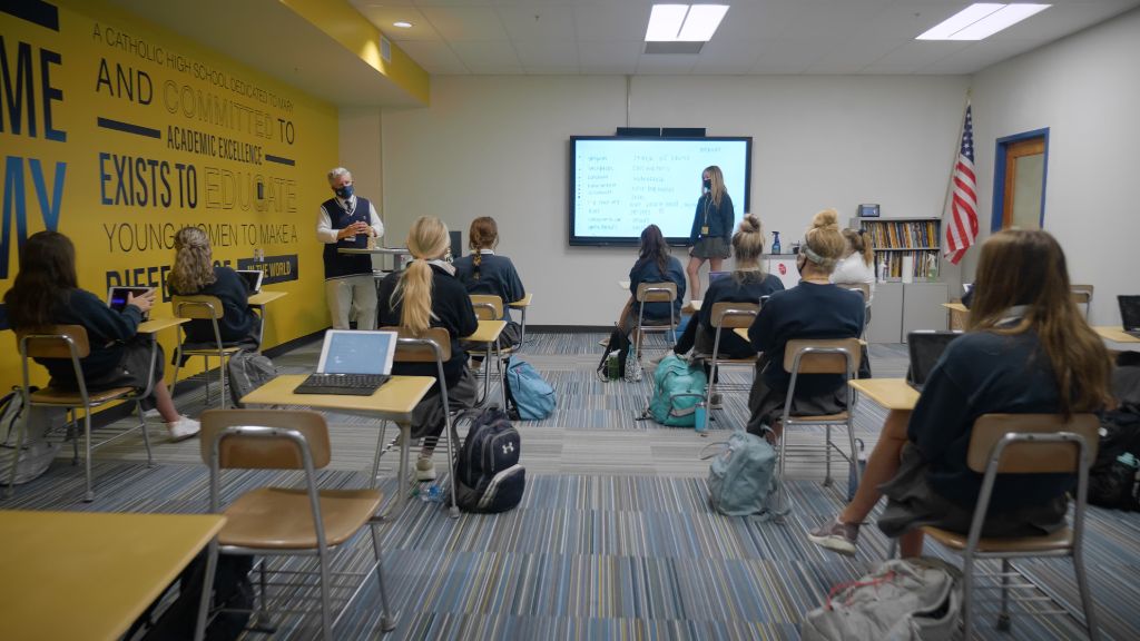 A view from the back of the classroom of students sitting socially distant wearing protective face masks while the teacher presents information at the Notre Dame Academy catholic all-girls school in Covington, Northern Kentucky.