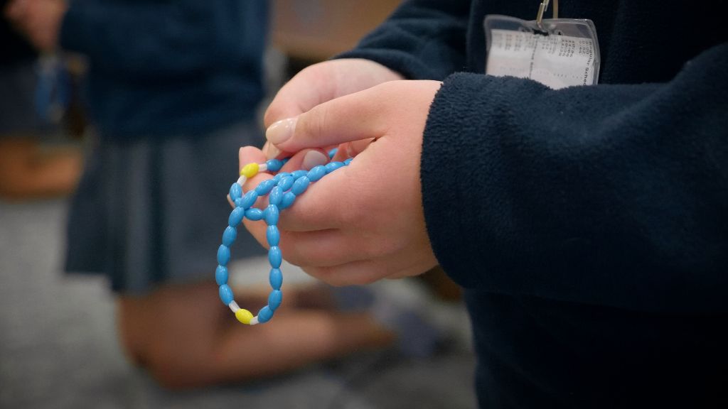 A close up of the hands of a student holding the rosary in prayer at the Notre Dame Academy catholic all-girls school in Covington, Northern Kentucky.