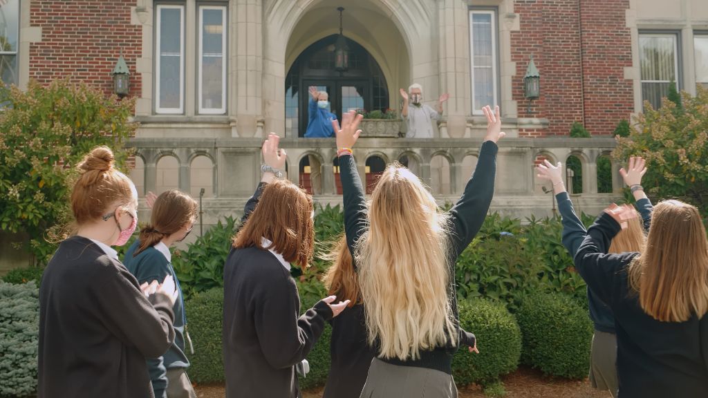 Students outside the school waving at teachers on the steps of the building at the Notre Dame Academy catholic all-girls school in Covington, Northern Kentucky.