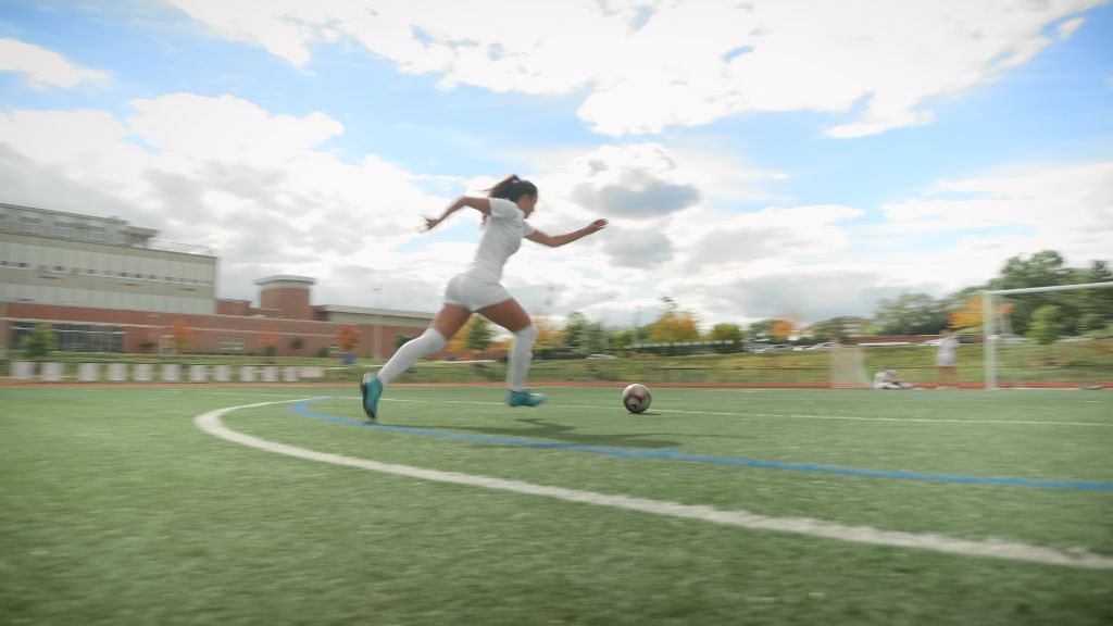 Student athlete soccer player sprinting across the field kicking a soccer ball at the Notre Dame Academy catholic all-girls school in Covington, Northern Kentucky.