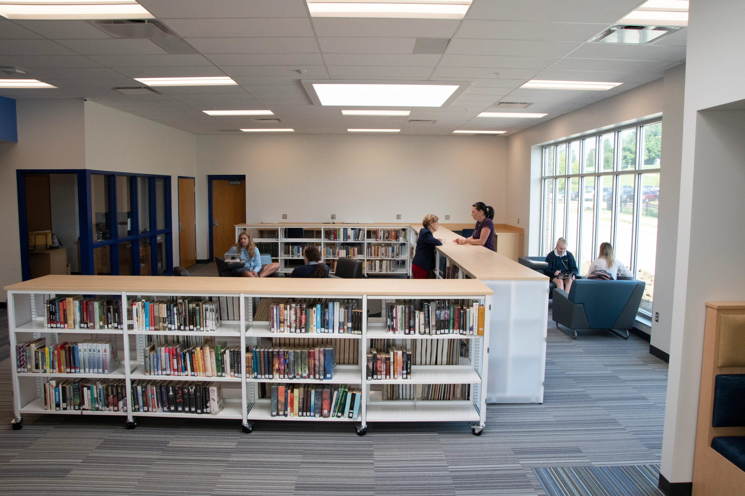 A view of the shelves filled with books and the students sitting and studying at chairs and tables in the Collaborative Learnin Center at Notre Dame Academy catholic all-girls school in Northern Kentucky.