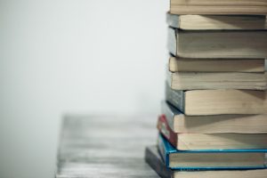 A pile of books sitting on a table off to the side of the frame.